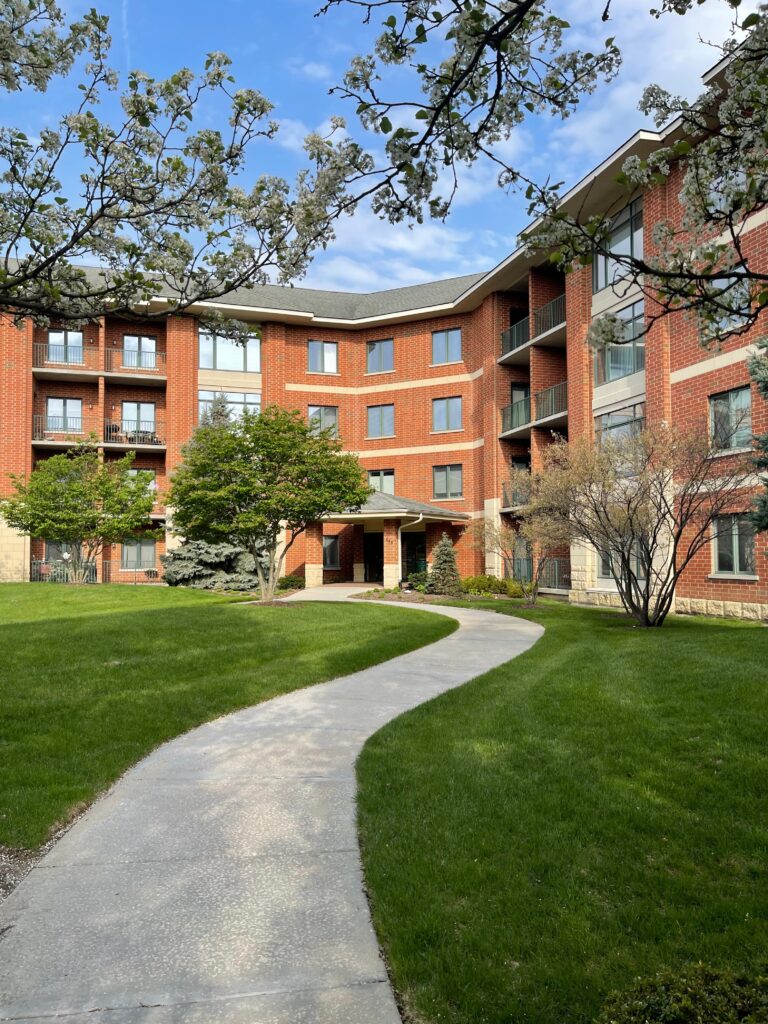 Brick Apartment Building With Trees And Curved Sidewalk